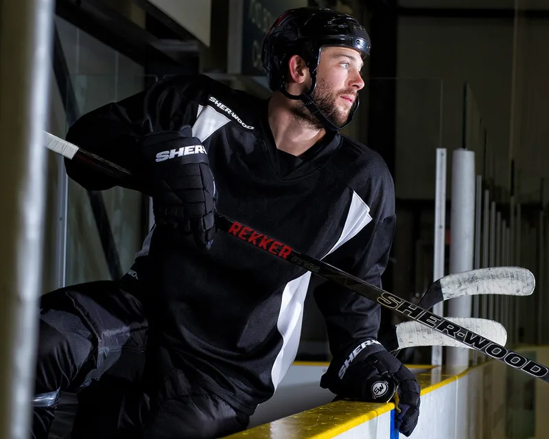 Eishockeyspieler mit Sher-Wood-Schläger an der Bande